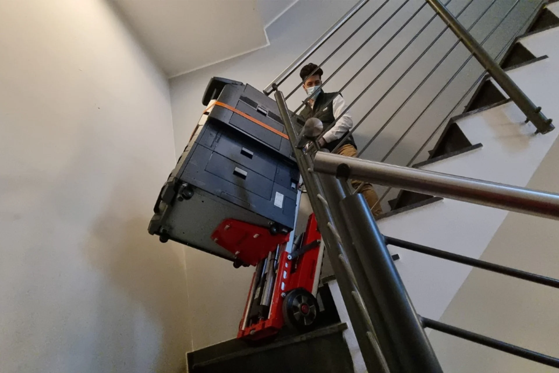 Technicus verplaatst printer via trap — logistieke dienstverlening